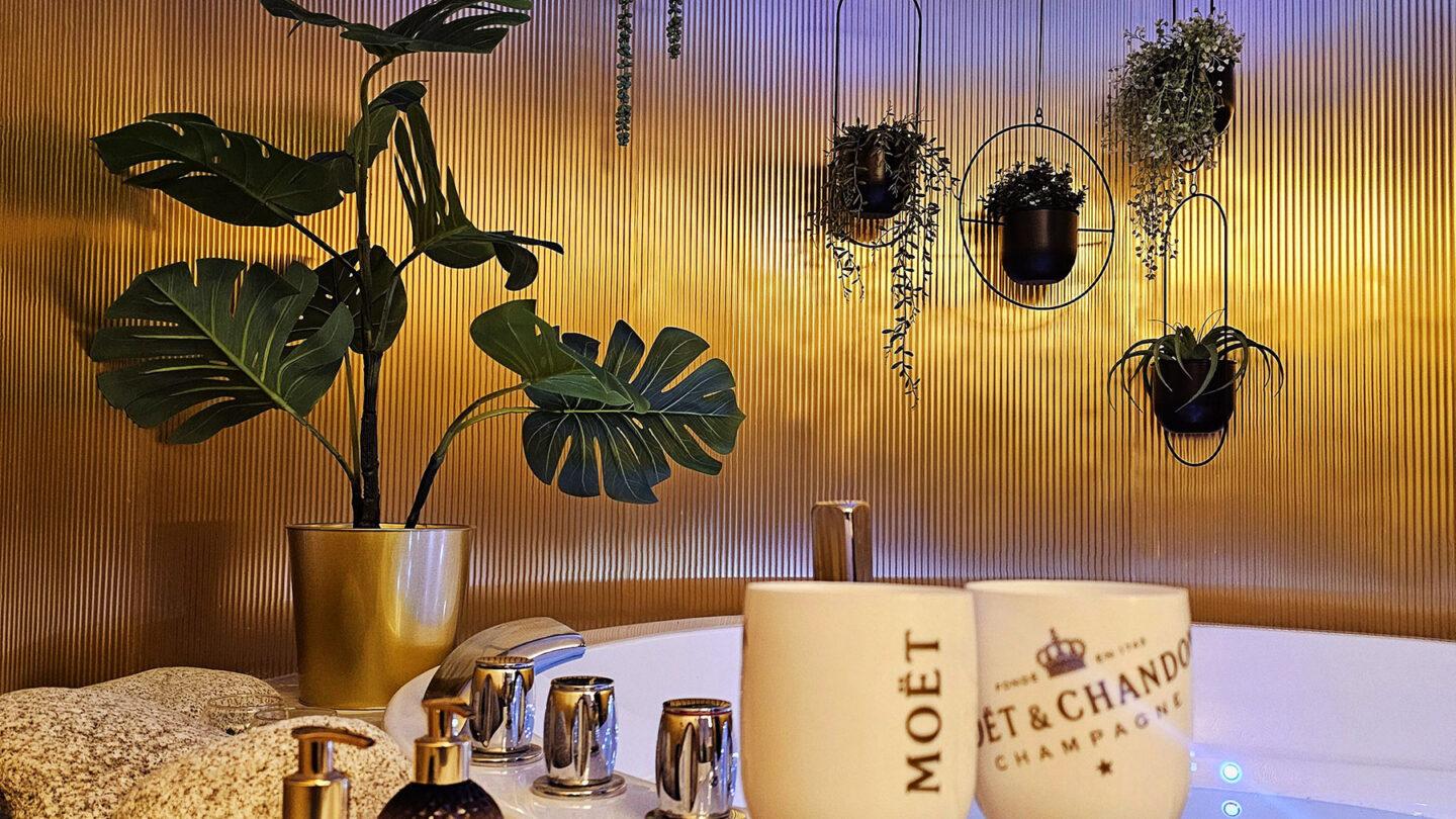 Elements fluted brass laminate wall with hanging planters beside a jacuzzi tub