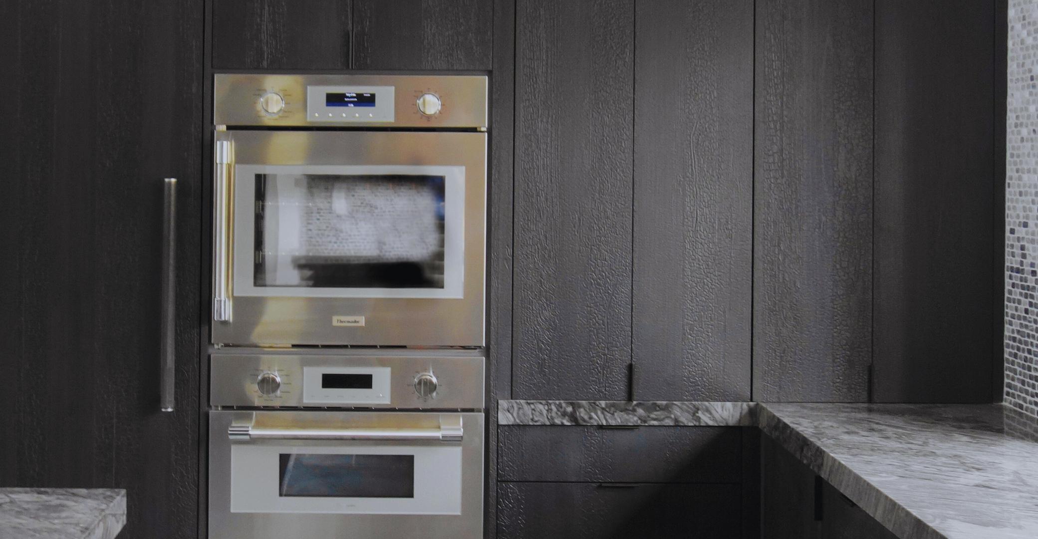 Prensa Bruciato Black embossed wood panel cladding kitchen cabinetry beside a built-in double wall oven
