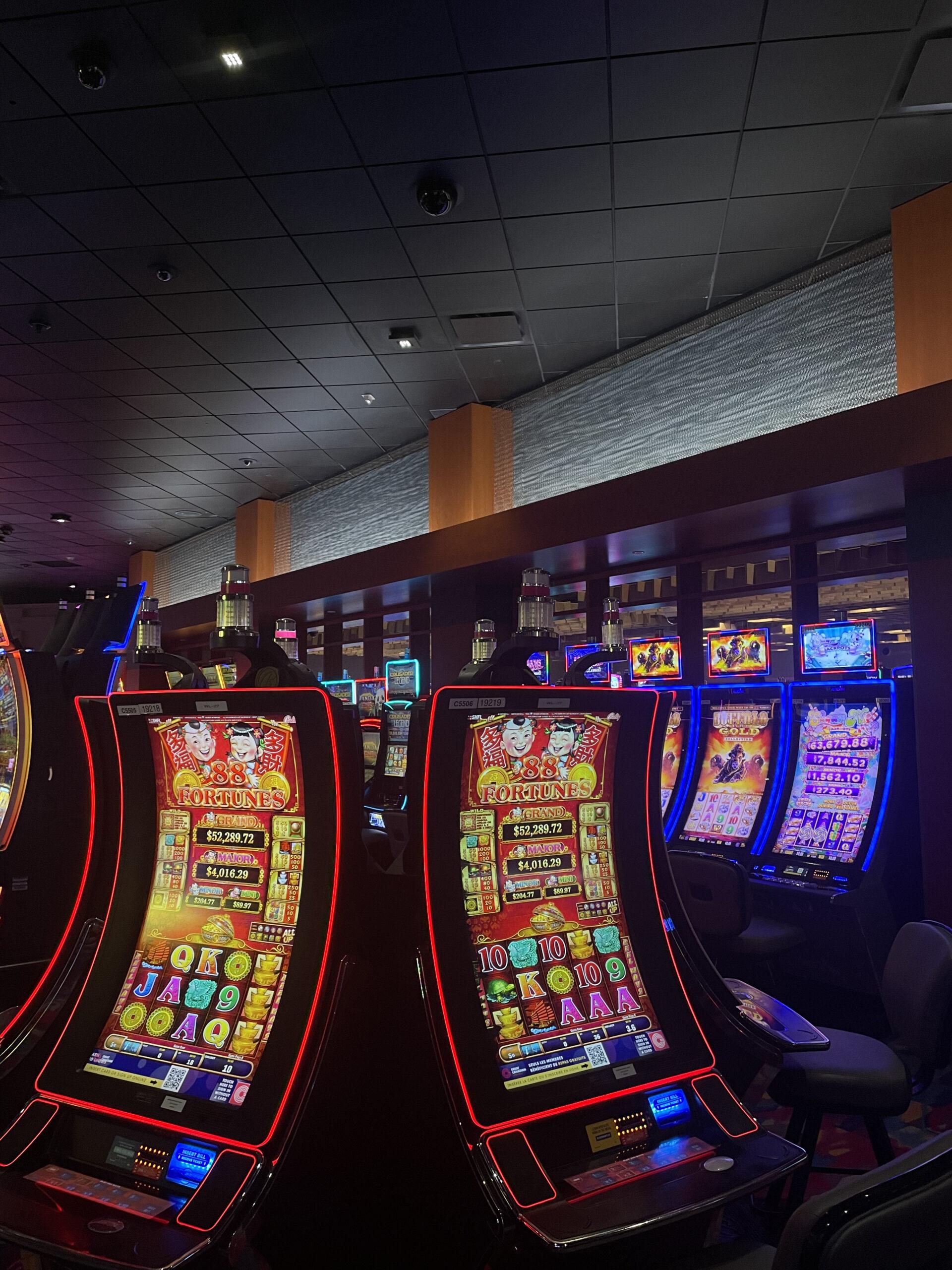 Luminous honeycomb mesh panel trim above slot machines, wider gaming floor view