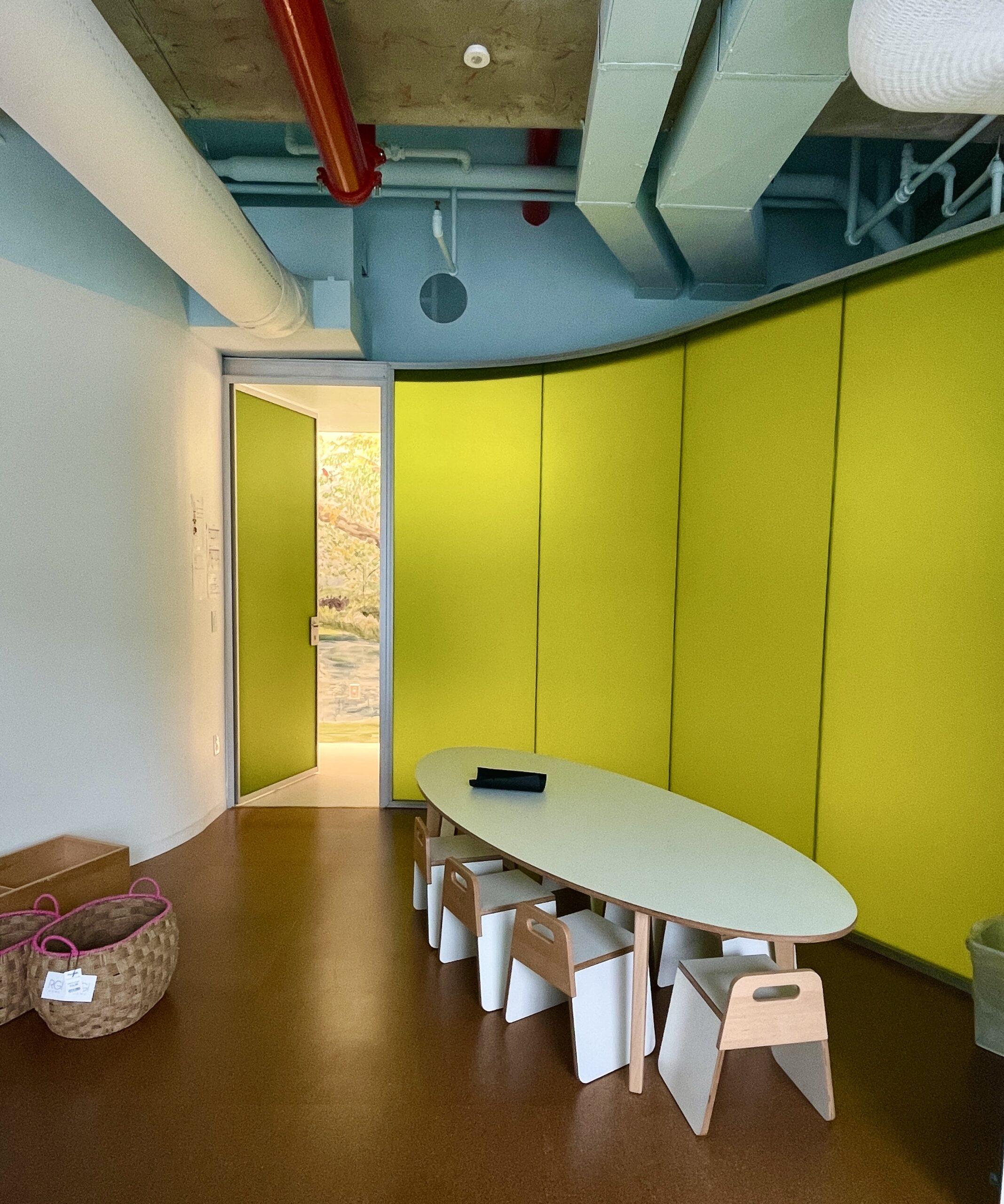 Luminous translucent honeycomb panel forming a curved yellow-green partition room with a kids' activity table