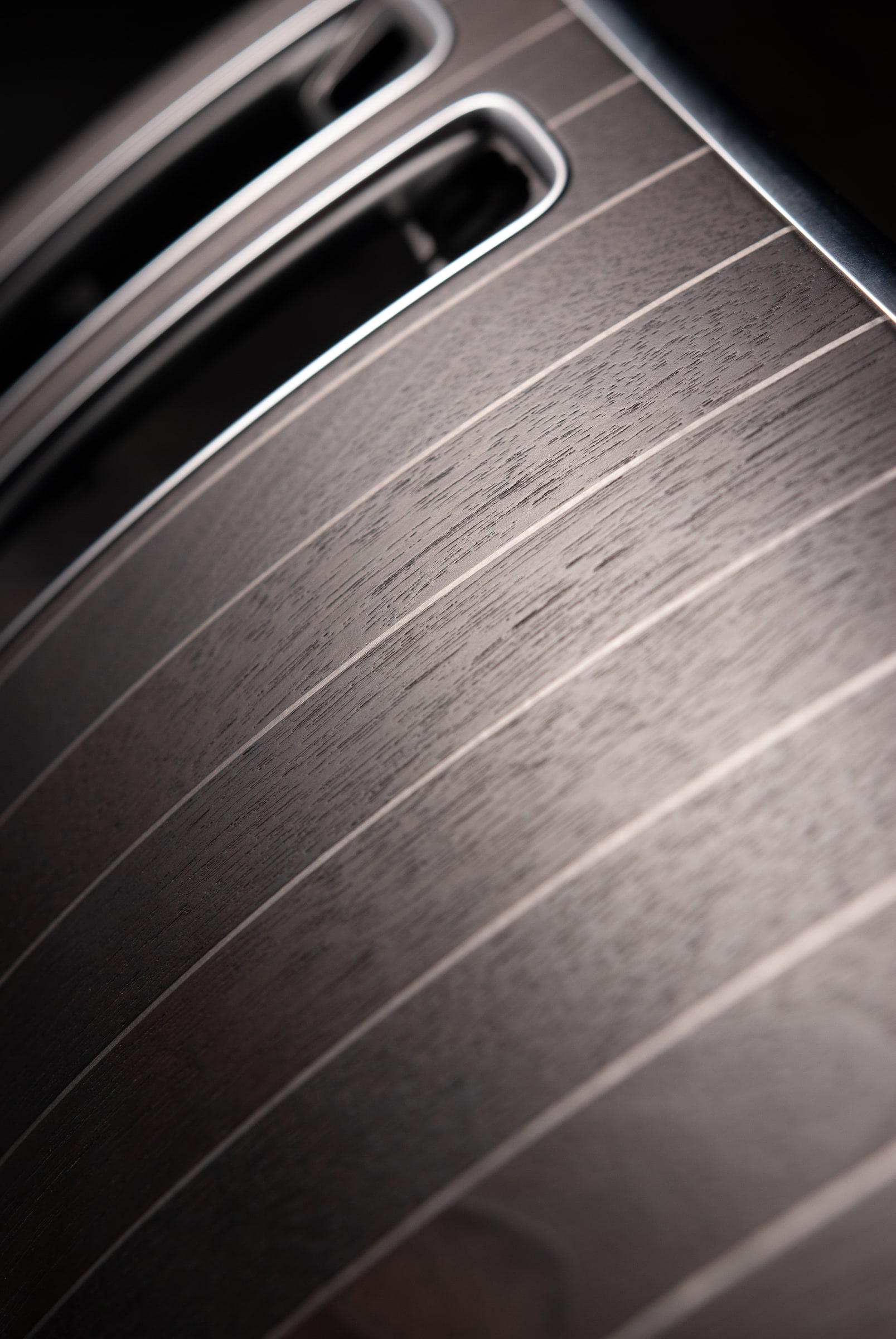 Close-up of Koncepts dark walnut veneer with fine metal stripe inlay on the Maybach console