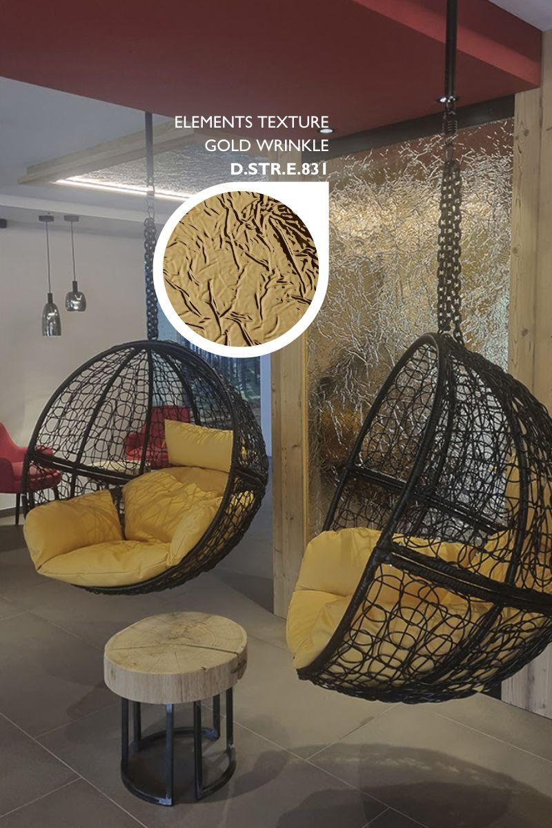 Elements Texture Gold Wrinkle laminate on a wall behind hanging egg chairs in a spa lounge