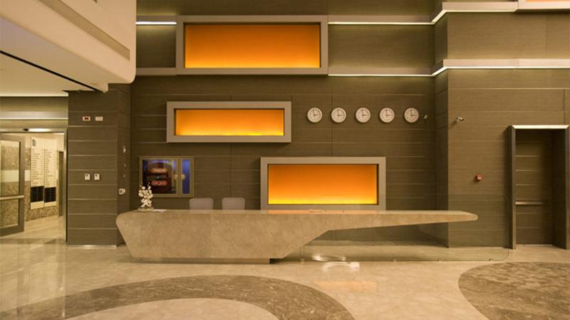 Backlit orange Luminous panels behind a hotel lobby reception desk