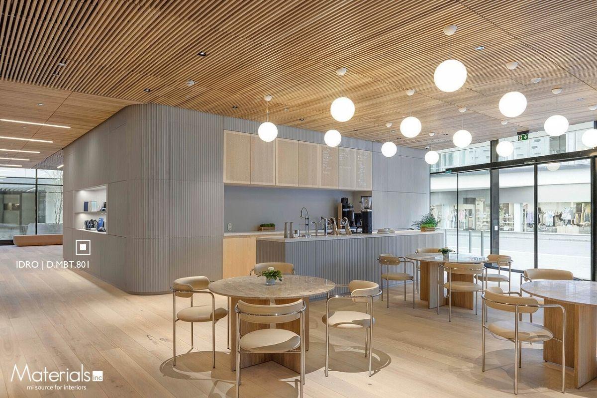 Aria Fluted Idro concrete panel cladding a curved café counter wall facing a street-level storefront