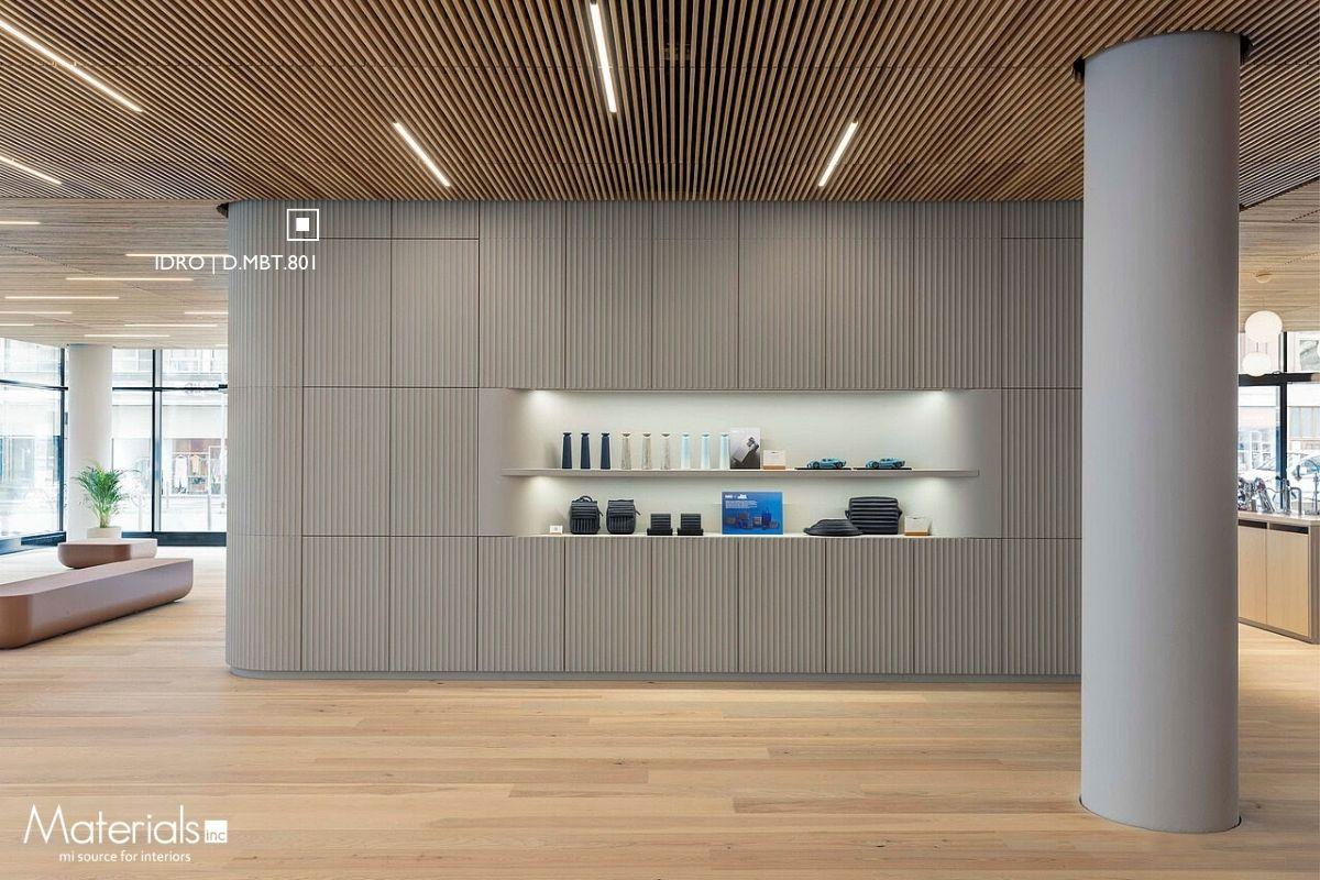 Aria Fluted Idro concrete panel cladding a curved retail display wall with lit product shelving