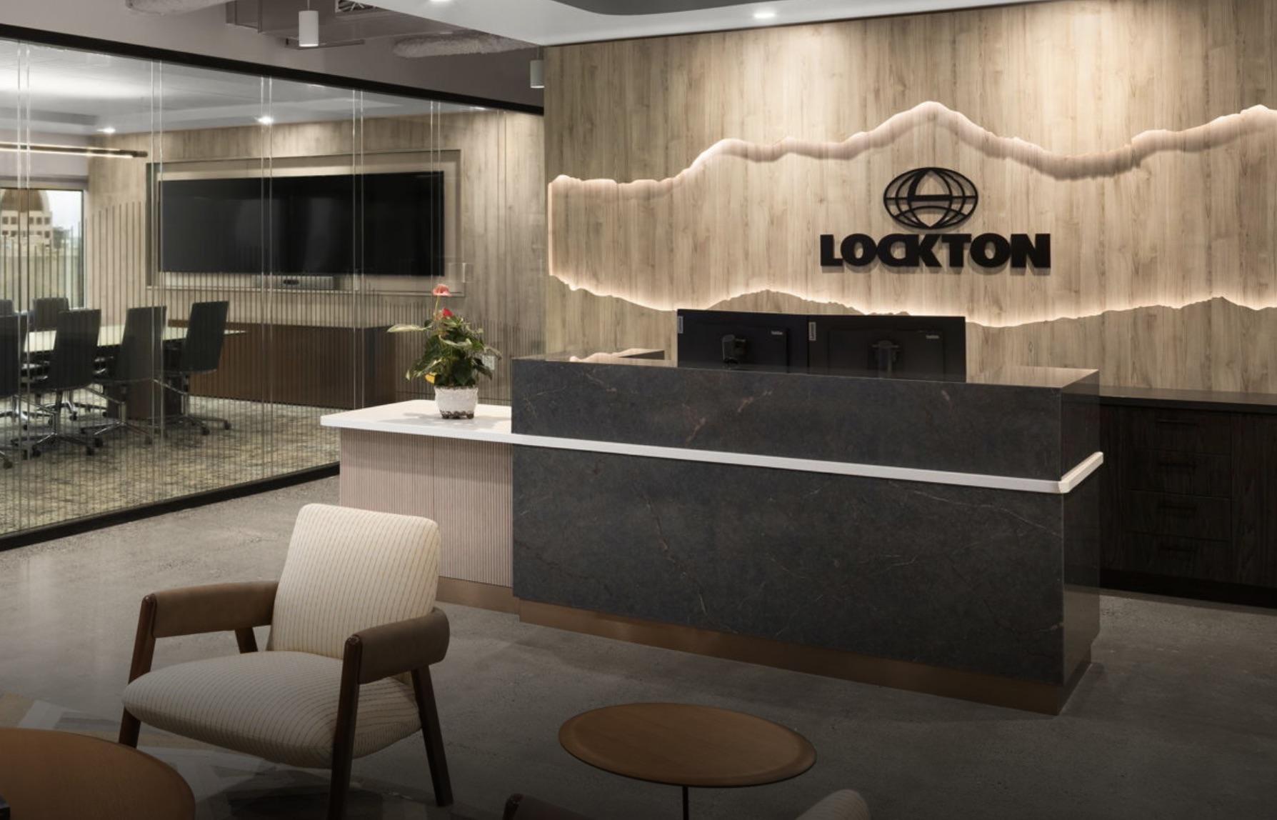 Tambora milled wood panel forming a backlit mountain-silhouette feature wall behind the Lockton office reception desk