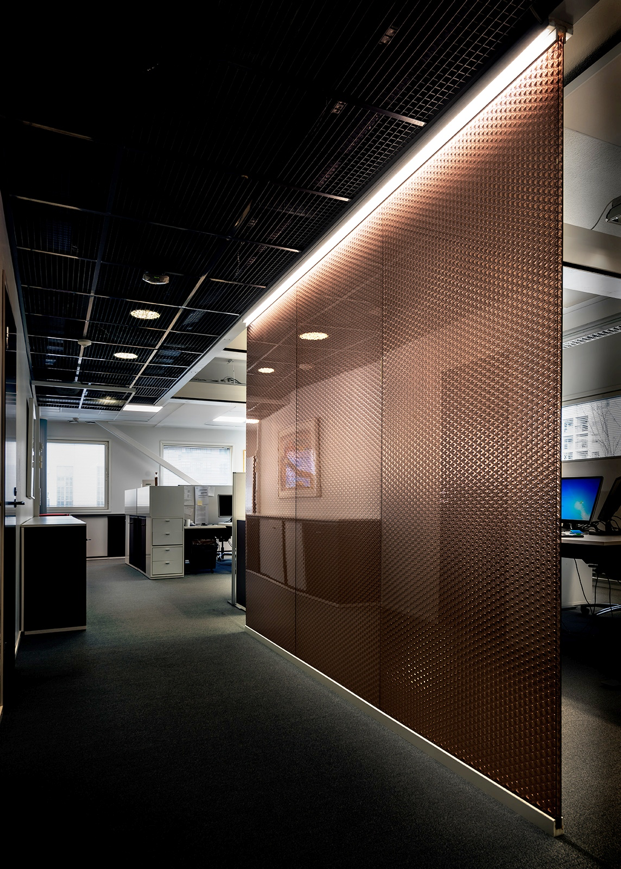 Backlit bronze Luminous honeycomb panel forming a corridor divider in an office