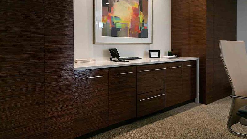 Prensa embossed wood panel on a built-in office credenza beneath framed abstract art