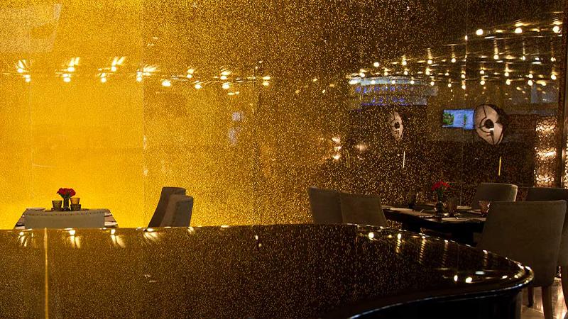 Shimmering gold backlit Luminous wall panel behind a restaurant bar
