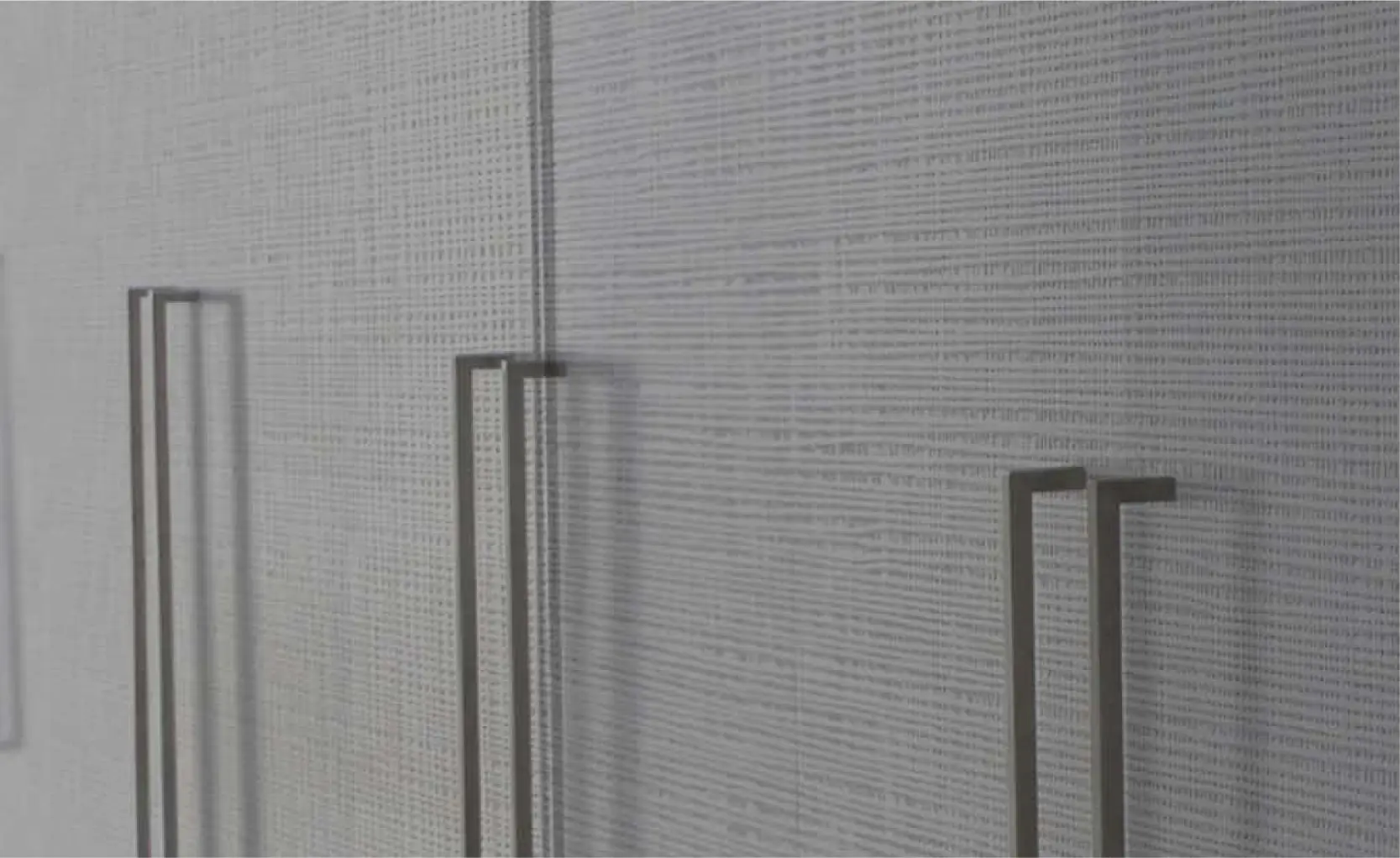 Close-up of Prensa woven-texture white embossed wood panel closet doors with slim vertical pulls