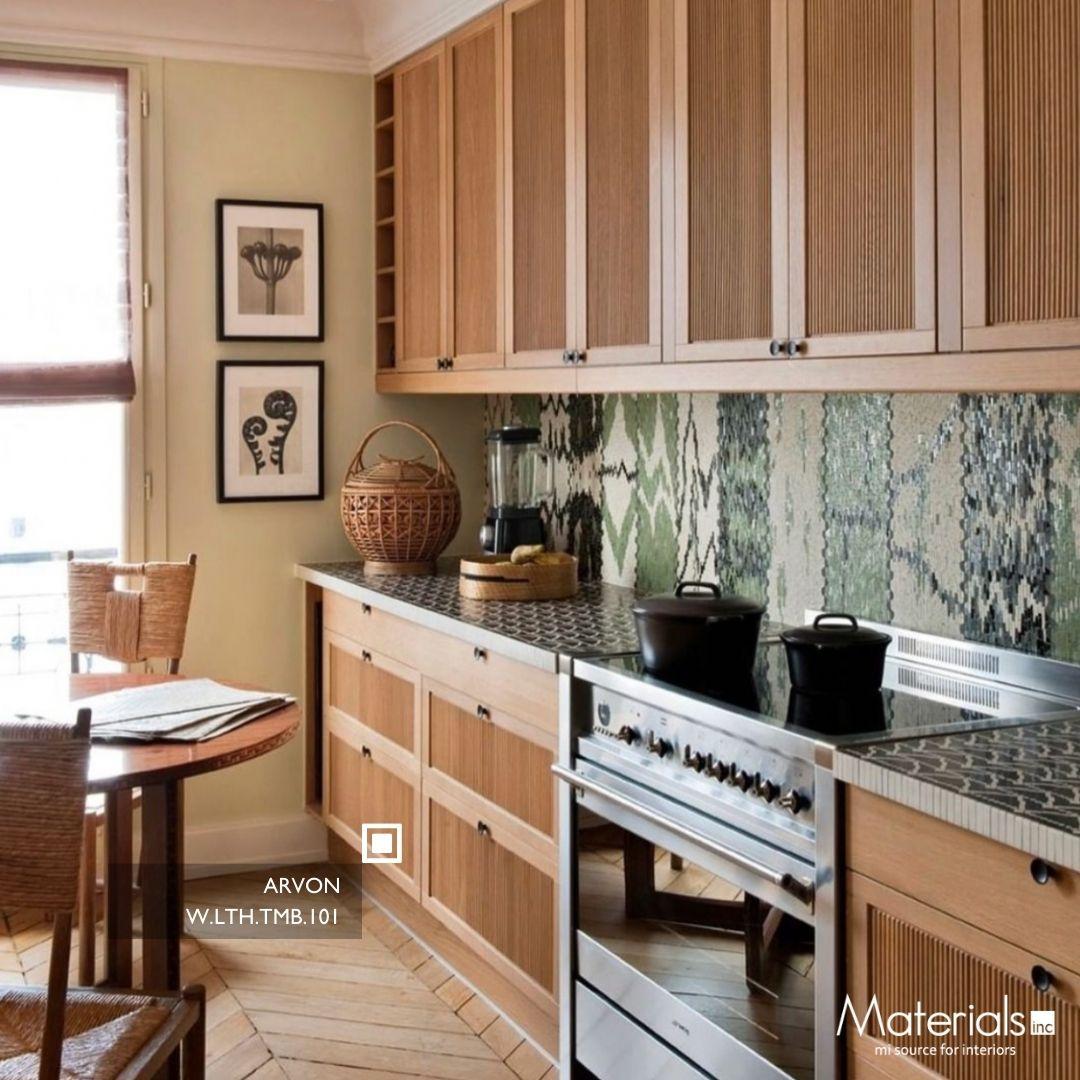 Tambora Arvon milled wood panel on upper cabinetry in a pale yellow kitchen with a green mosaic backsplash